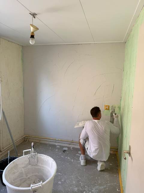 Stukadoor zet de stuclaag op een wand