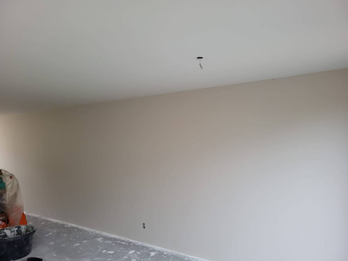 Strakke wand in greige onder een wit plafond